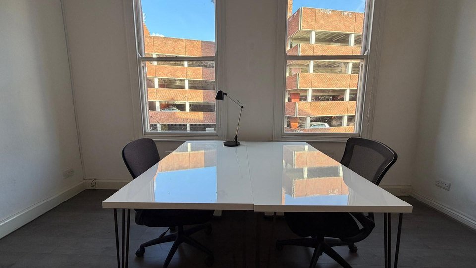 2 desks in front of a window